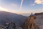 Oman, Wadi Ghul, Jebel Shams. The Grand canyon of Oman, tourist on the edge looking at view, at sunrise (MR)