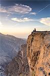 Oman, Wadi Ghul, Jebel Shams. The Grand canyon of Oman, tourist on the edge looking at view, at sunrise (MR)