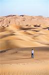 United Arab Emirates, Abu Dhabi. Tourist walking, Rub Al Khali (Empty quarter) desert at sunrise (MR)