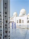 United Arab Emirates, Abu Dhabi. Two arabic men in traditional dress walking inside Sheikh Zayed Grand Mosque