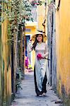 Vietnam, Hoi An. Young vietnamese girl with Ao Dai dress walking in a alley (MR)