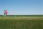 Three people running through field