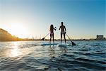 Rear view of two women stand up paddleboarding, Mission Bay, San Diego, California, USA