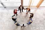 Overhead view of businessmen and women in circle holding hands