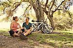 Mature cyclist couple taking a water break in park