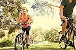 Mature couple cycling through park