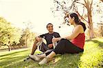 Mature running couple taking a break and drinking water in park