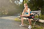 Portrait of smiling female runner taking a break on park bench