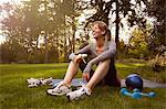 Mid adult woman sitting in park taking exercise break