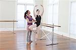 Teacher teaching ballet position to teenage ballerina  at ballet school