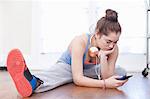 Teenage girl warming up and looking at smartphone in ballet school