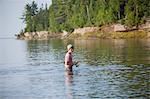 Wading teenage boy fishing in Lake Superior, Au Train Bay, Michigan, USA