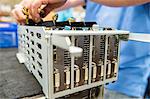 Midsection of male engineer repairing video card at table in electronics industry