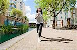 Full length of fit young woman jogging by canal against buildings