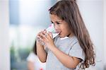 Cute girl drinking glass of water at home