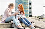 Full length of smiling female college students studying on steps against building