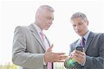 Businessmen discussing over mobile phone outdoors