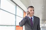 Middle aged businessman using mobile phone at train station