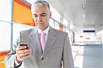 Middle aged businessman text messaging through cell phone at railroad station
