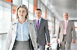 Beautiful young businesswoman walking with male colleagues in background at train platform