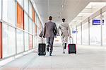 Full length rear view of businessmen with luggage running on railroad platform