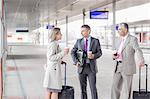 Businesspeople with luggage talking on railroad platform