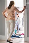 Full-length rear view of mother watching daughters trying on clothes in room