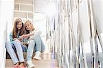 Full-length of sisters listening to music on stairway