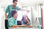 Businessman showing something to colleagues on computer in creative office