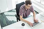 High angle view of businessman using laptop at desk in creative office