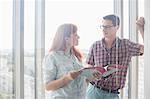 Business colleagues discussing over file in creative office