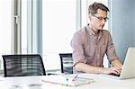 Businessman using laptop at desk in creative office