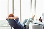 Side view of businesswoman relaxing with feet up at desk in creative office