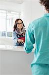 Smiling businesswoman handing over to male colleague at counter in creative office