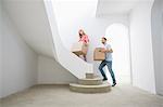 Couple carrying cardboard boxes up stairs in new house