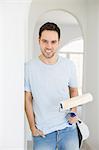 Portrait of handsome man holding paint roller in new house