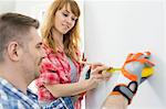 Couple using tape measure on wall