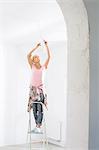 Woman on ladder fitting light bulb in new house