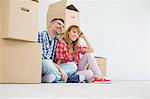 Full-length of happy couple sitting in new house