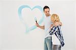 Loving mid-adult couple with painted heart on wall