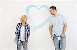 Mid-adult couple looking at each other with painted heart on wall