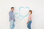 Mid-adult couple looking at each other with painted heart on wall