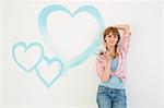 Portrait of beautiful woman holding paint brush with hearts painted on wall