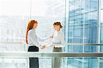 Happy businesswomen shaking hands in office