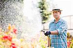 Man watering plants outside greenhouse