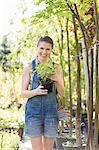 Portrait of happy woman holding potted plant at garden