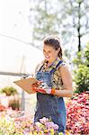 Happy female supervisor writing on clipboard outside greenhouse