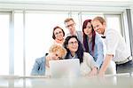 Happy business colleagues with laptop discussing in creative office