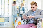 Businessman using tablet PC with colleagues discussing in background at creative office