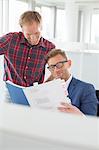 Businessmen reading file in creative office